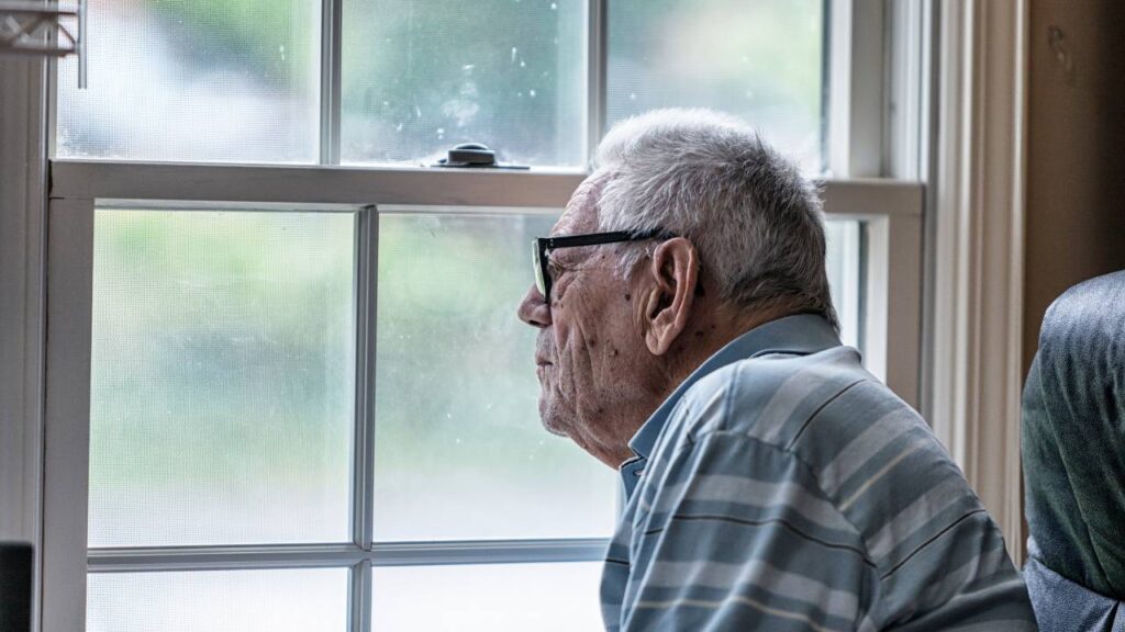Elderly man staring through window
