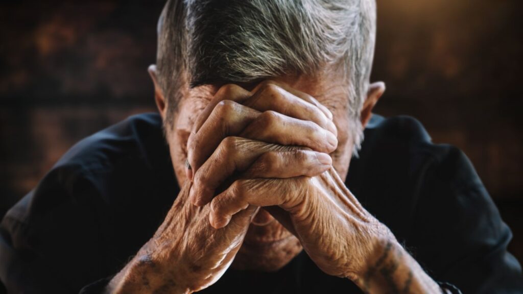 Senior man covering his face with his hands