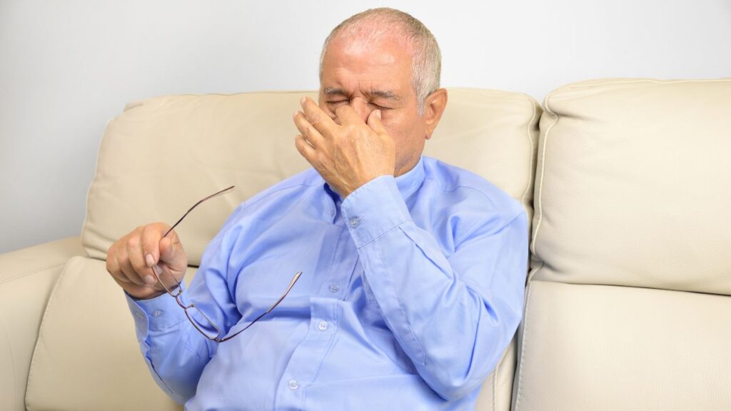 Senior man looking stressed sitting on a couch at home