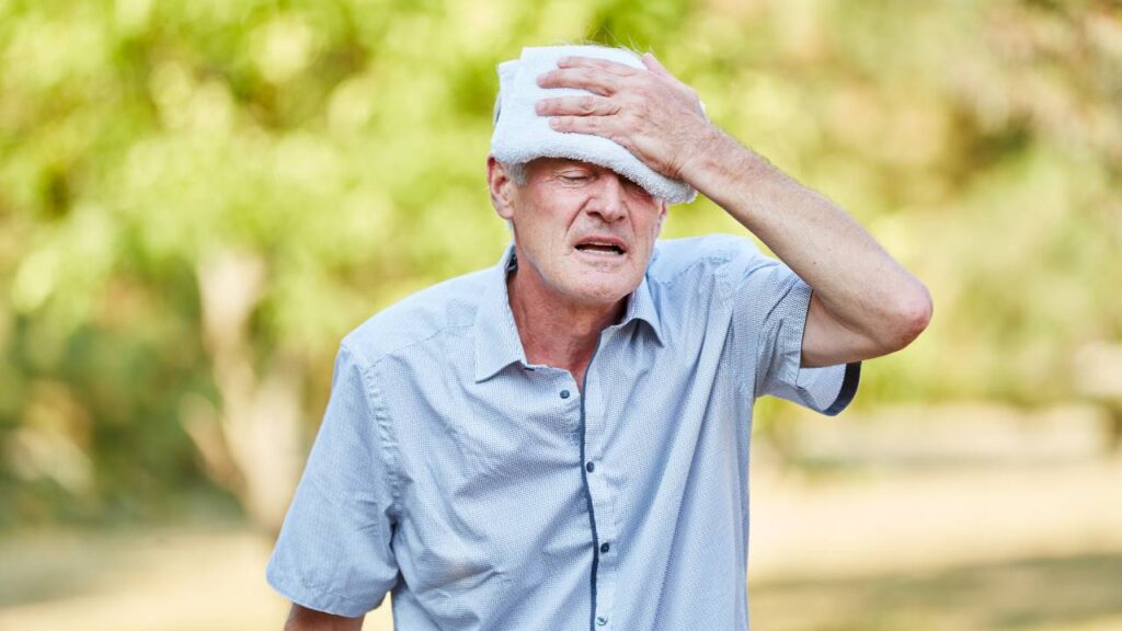 Senior man with bad circulation cools his head with wet cloth