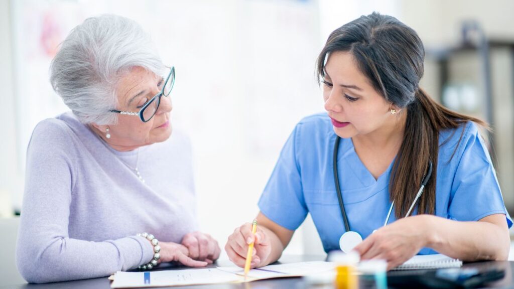 Senior woman reviewing medications by a female nurse