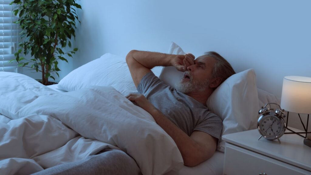 Sleepy senior man in bed at home
