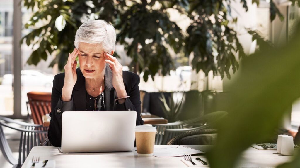 Stressed senior businesswoman using laptop while sitting in a cafe