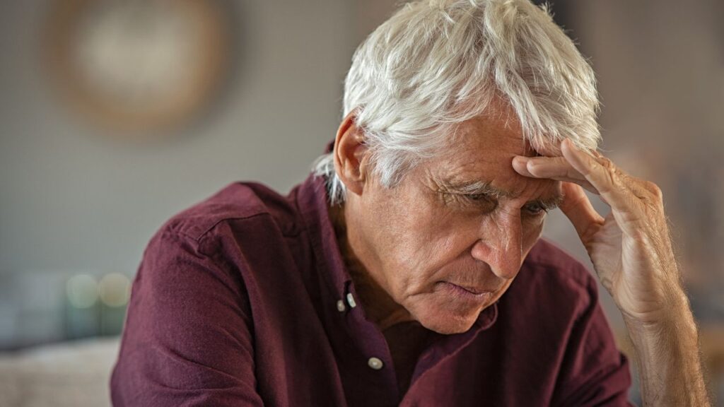 Tired and stressed senior man with hand on head