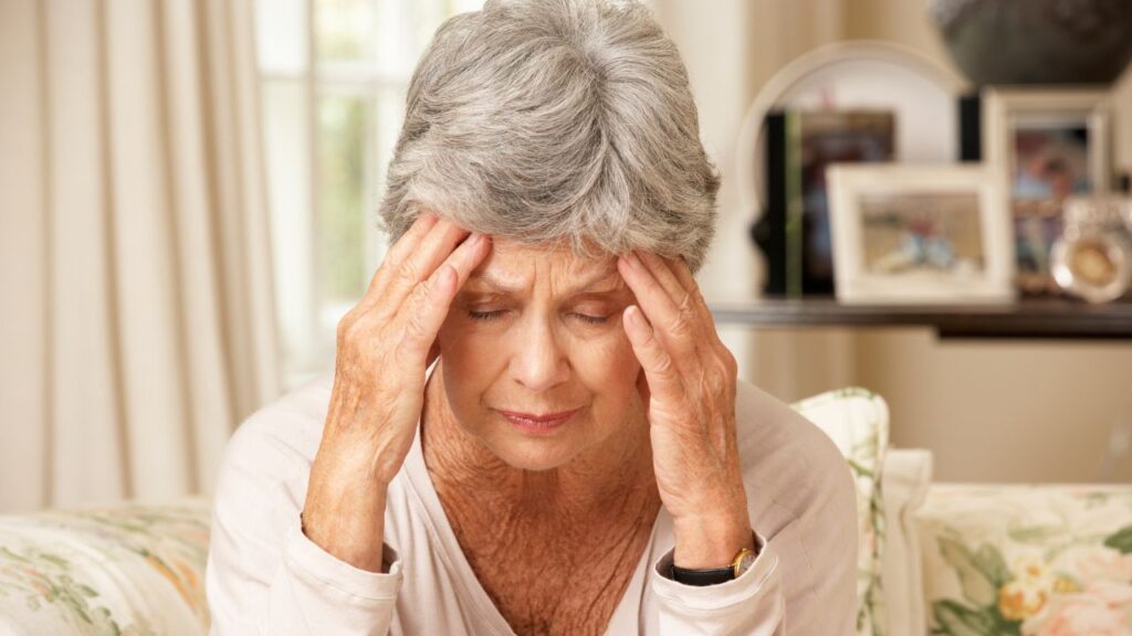 Unhappy Retired Senior Woman Sitting On Sofa At Home
