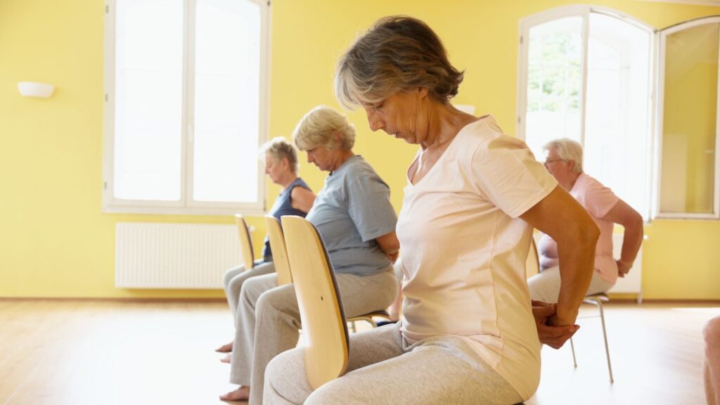 Senior women exercising on chair during yoga class